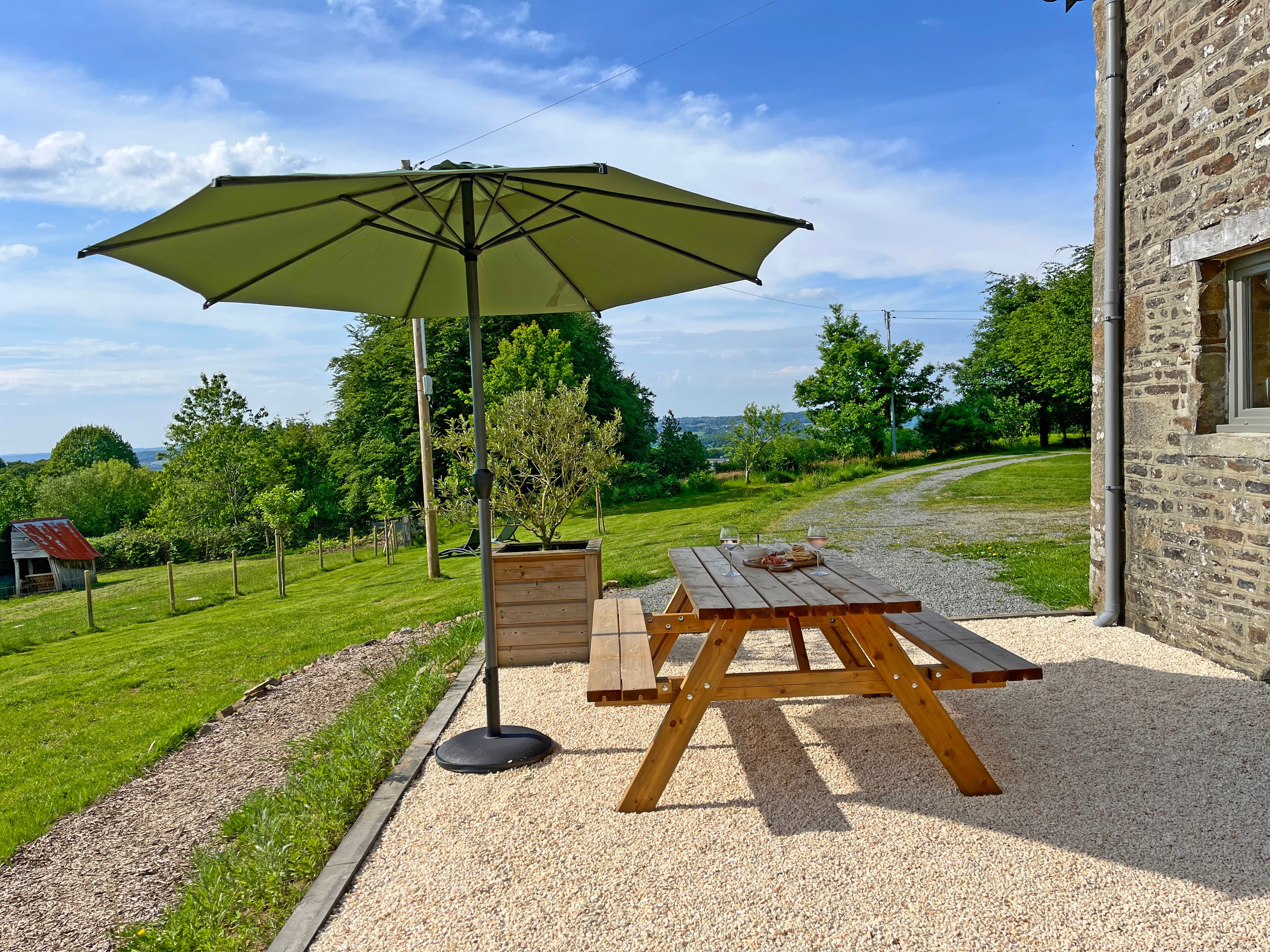 Ons gezellige terras met picknicktafel en parasol van Gîte La Cour de Haut